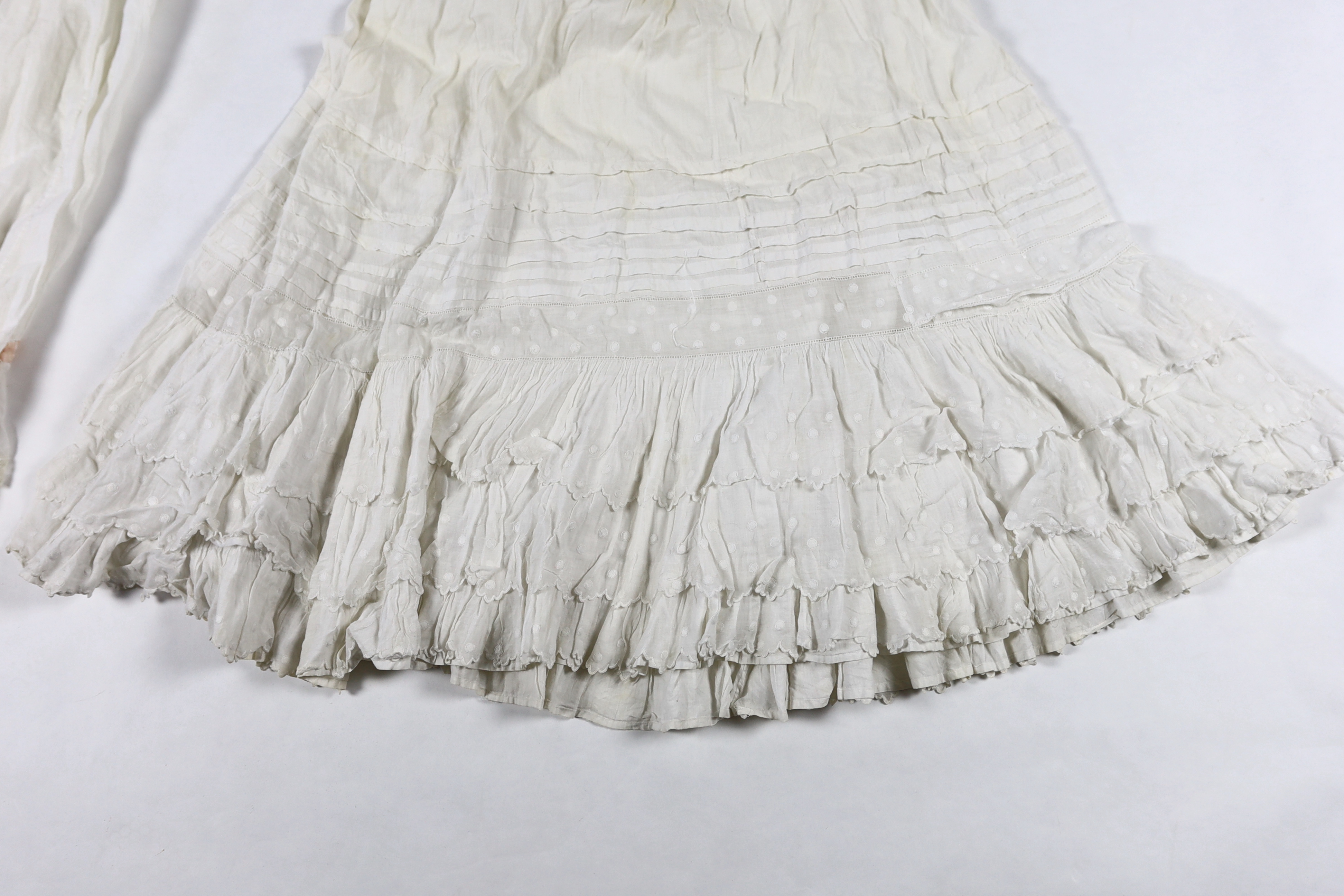 Three Victorian white worked petticoats; one two tiered, one lace trimmed with ribboning, the third worked with cutwork border, all approx. 94cm long